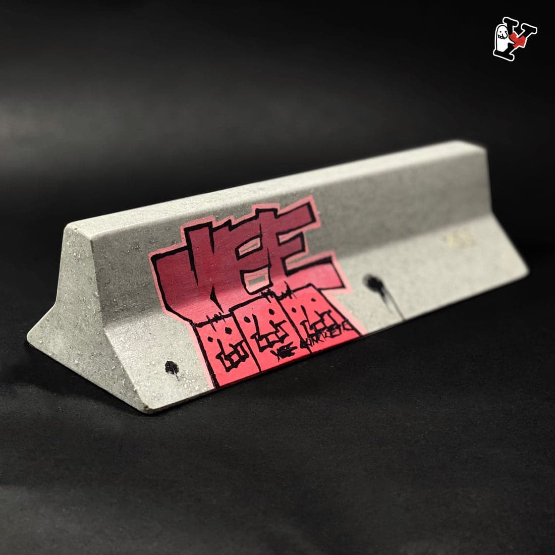 A low concrete YEE A-Barrier fingerboard obstacle with graffiti.