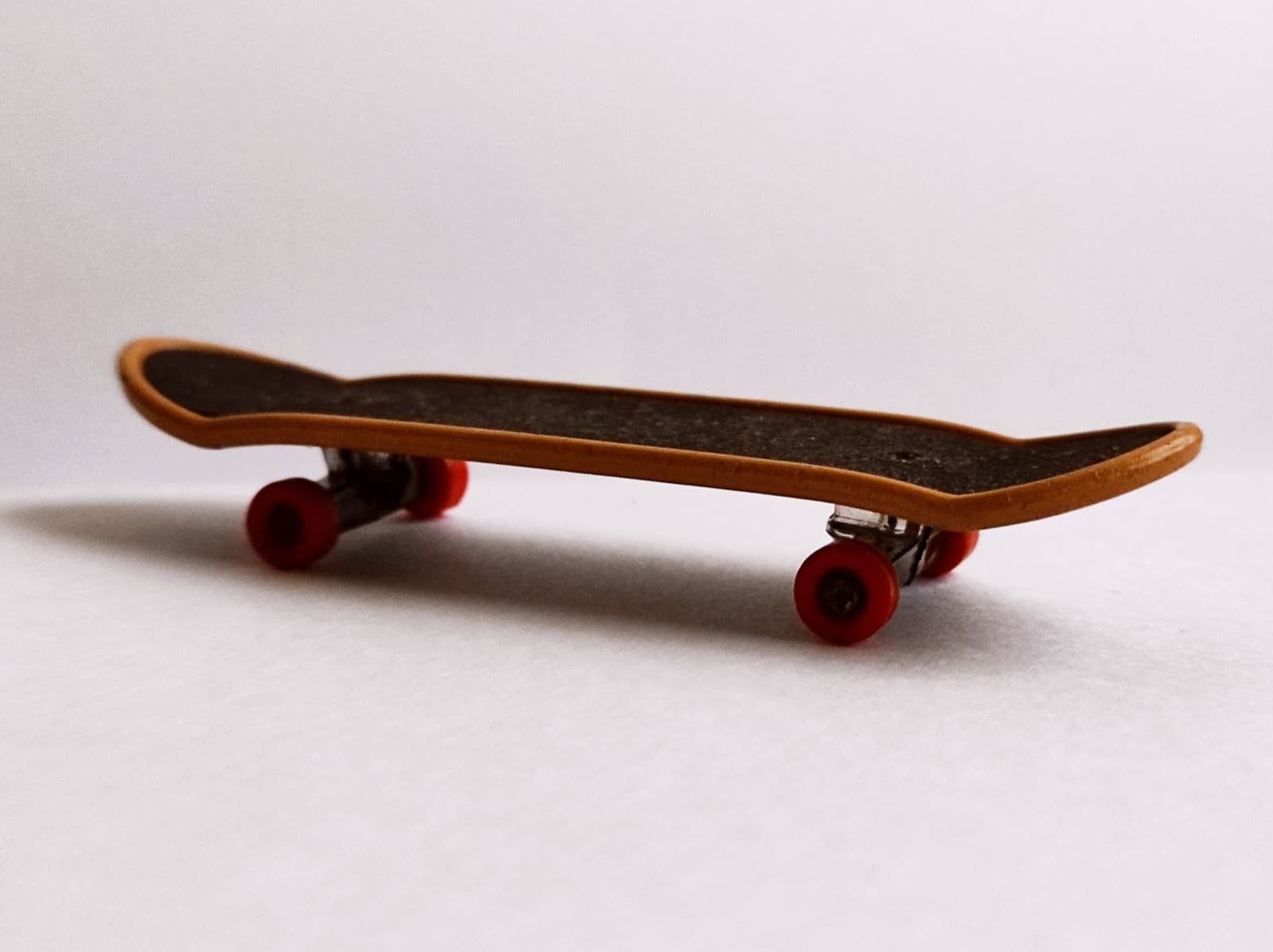 A close-up of a modern fingerboard with colored urethane wheels.