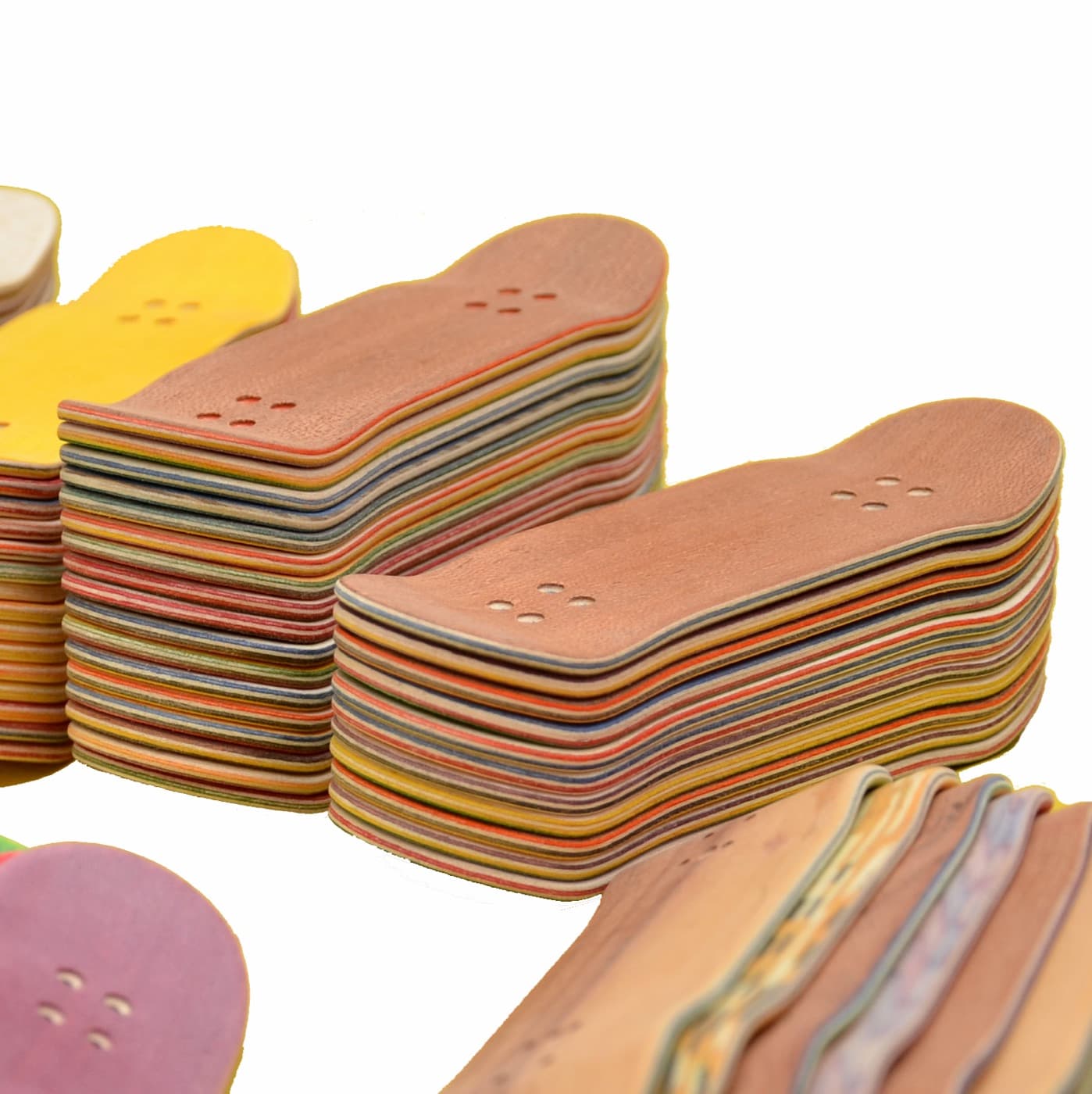 Stacks of freshly pressed multi-ply Finga fingerboard decks with colored veneer layers.