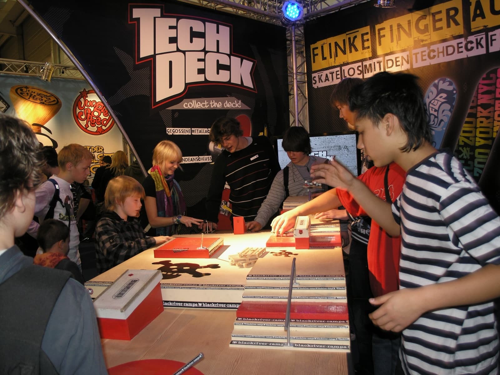 Young fingerboarders gathered around obstacle tables at a 2008 convention booth.