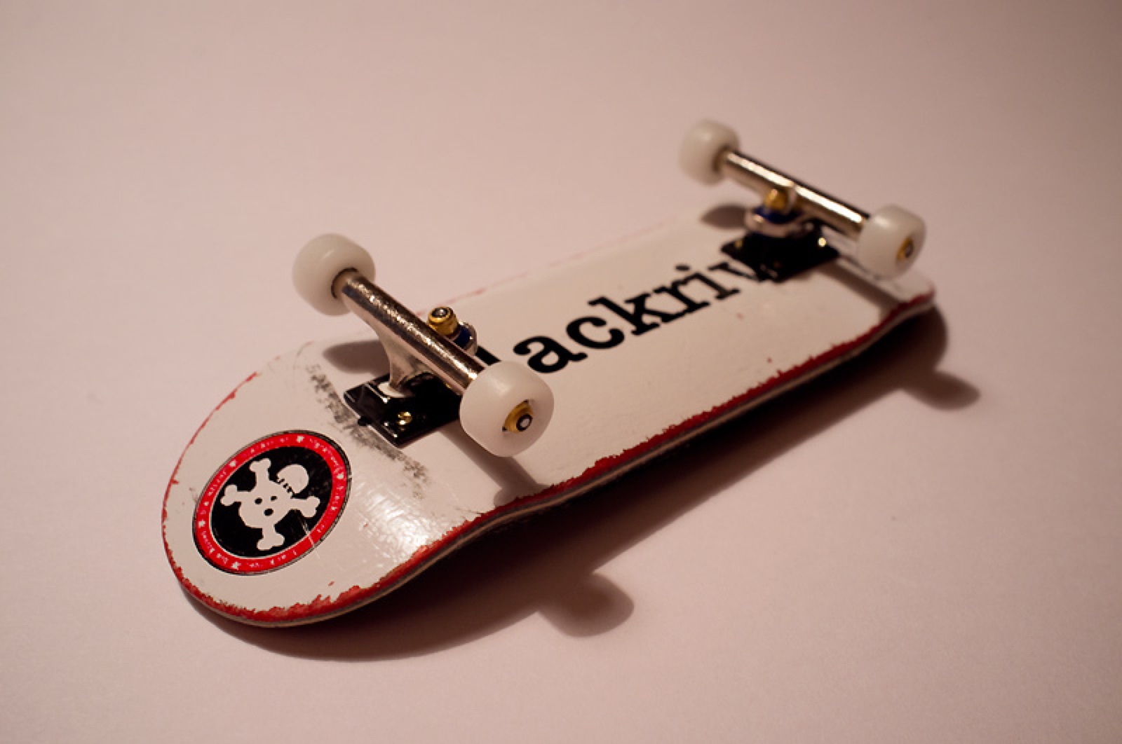 A professional fingerboard complete setup with a wooden deck, metal trucks, and wheels.