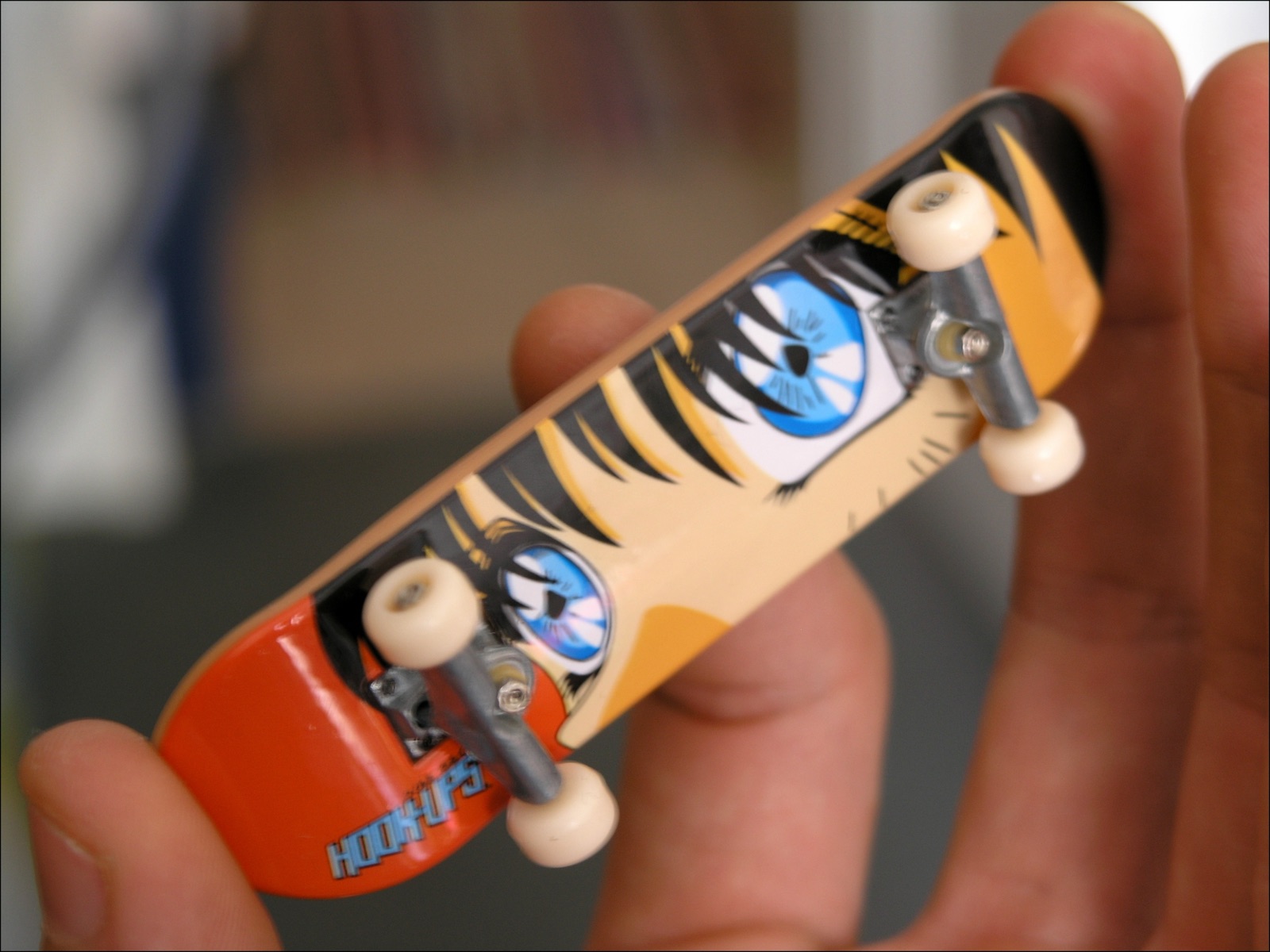 A wooden fingerboard deck shown on a plain surface.