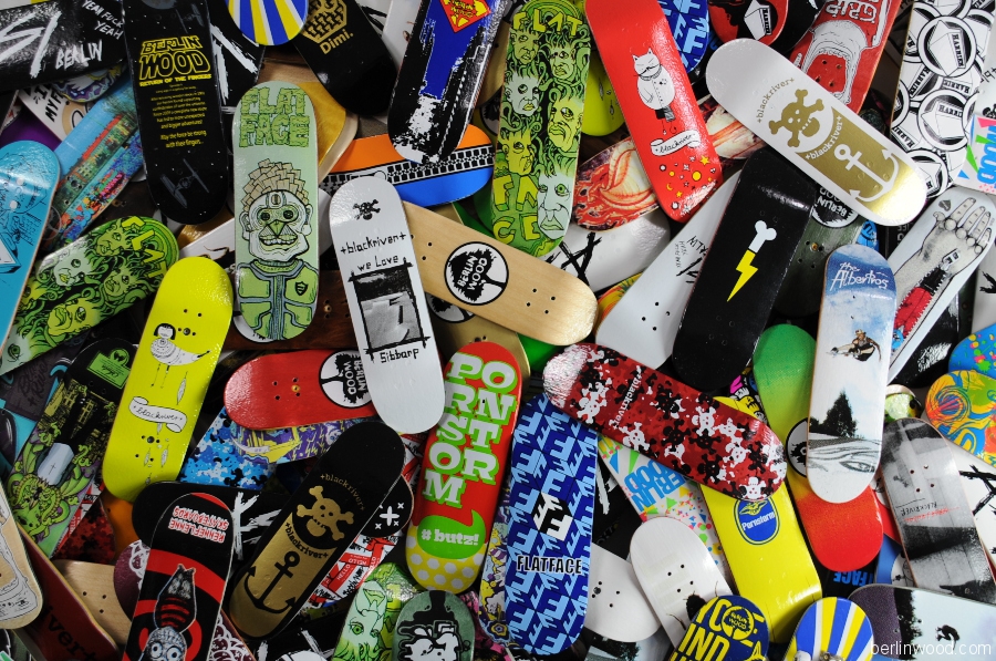 Dozens of boutique wooden fingerboard decks with colorful hand-finished graphics piled edge to edge.