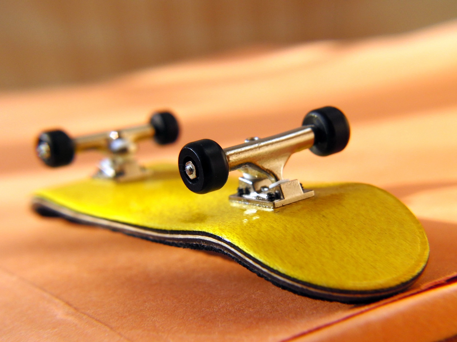 A professional wooden fingerboard with metal trucks and bearing wheels.
