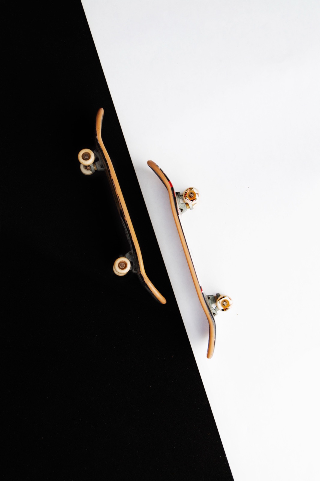 Two miniature fingerboard skateboards on a black-and-white surface.