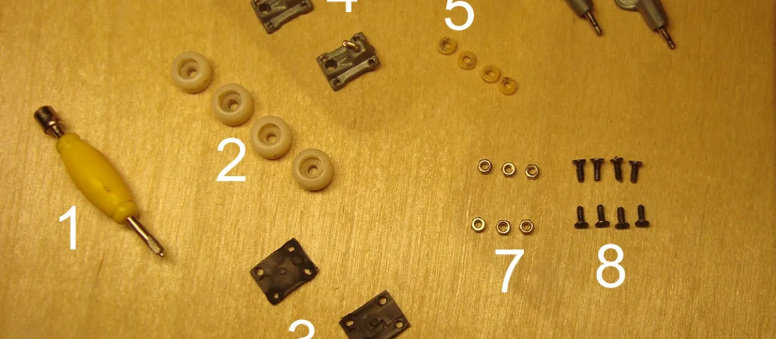 Fingerboard wheels, mounting hardware, and tuning parts laid out on a wooden surface.